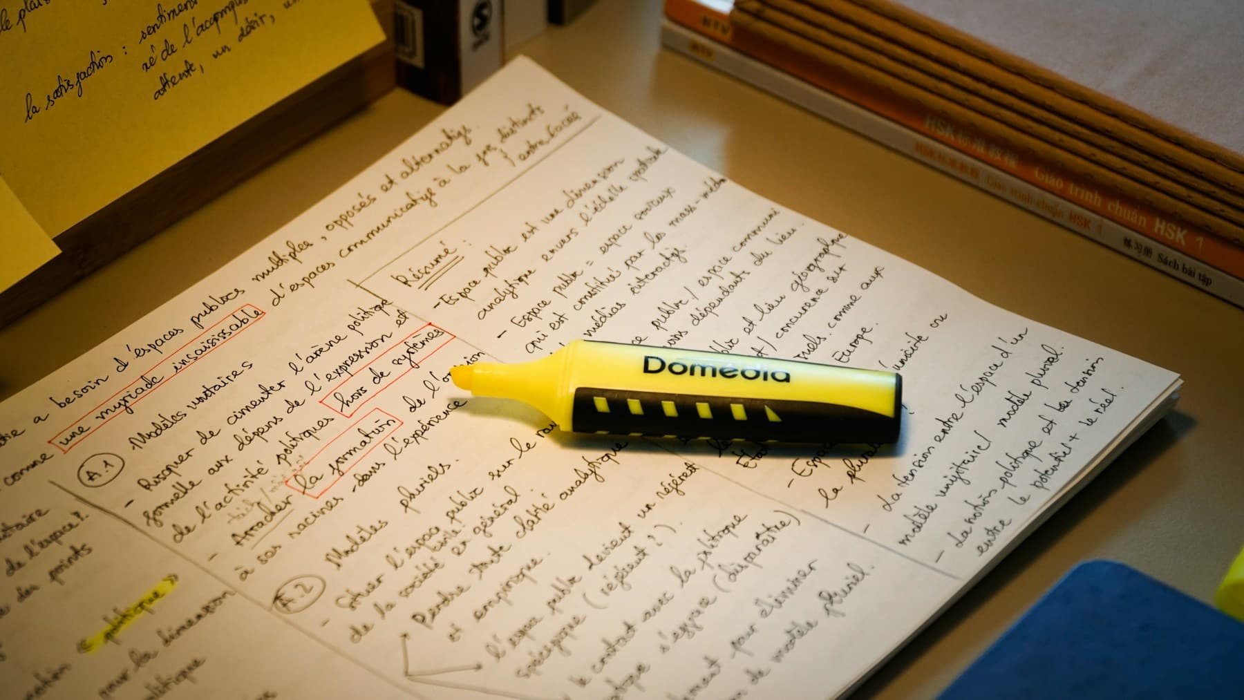 A yellow highlighter resting on handwritten study notes